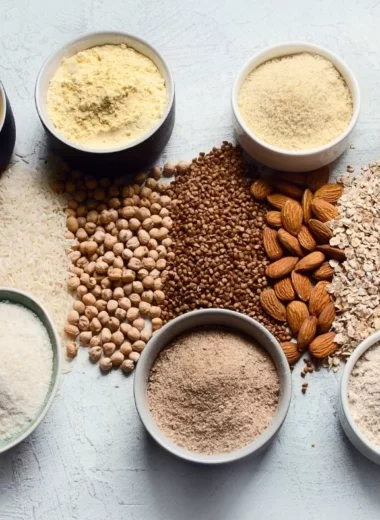 Different gluten-free flours, nuts, and grains arranged on a board.
