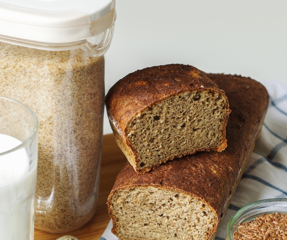 Psyllium husk bread on a cutting board with whole flaxseeds, psyllium husk and milk.
