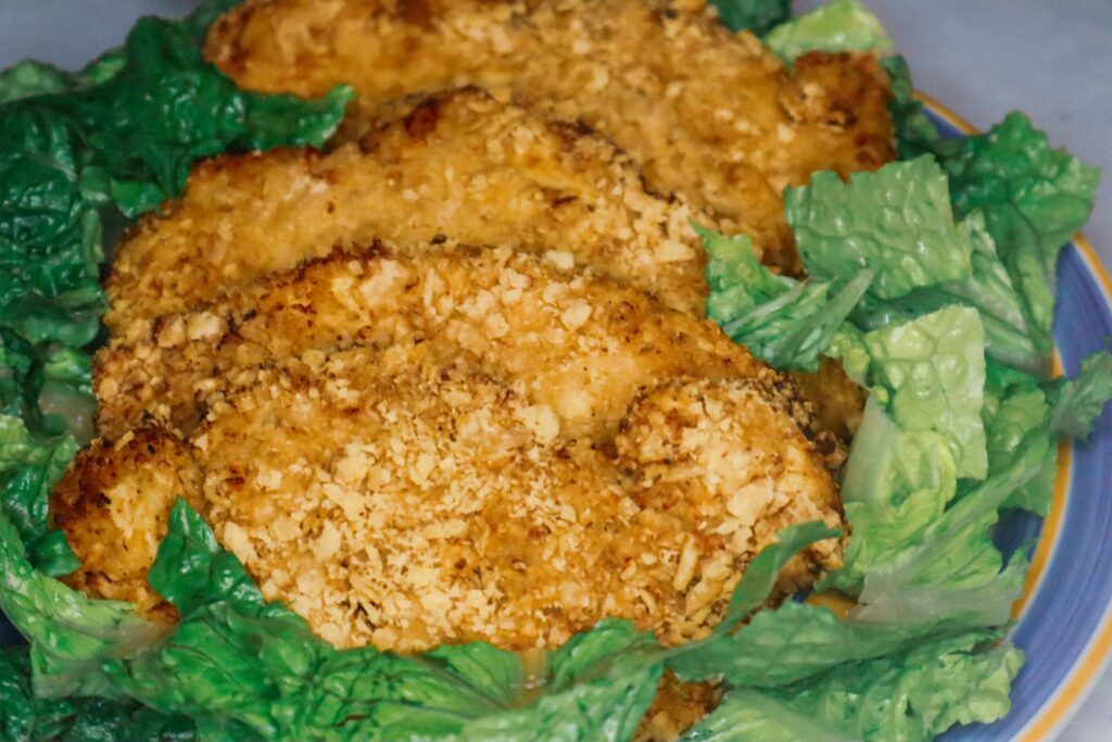 Air fryer sour cream and onion chicken on a plate garnished with Romaine lettuce.