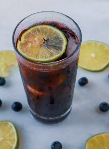 Blueberry Lime Refresher in a glass garnished with lime slices and blueberries.