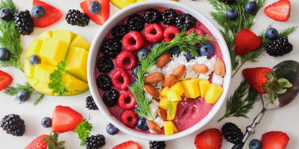 Foods to eat in moderation: a fruit smoothie bowl surrounded by fruit.