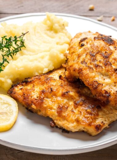 Mashed potatoes with fried chicken cutlets and lemon slices.