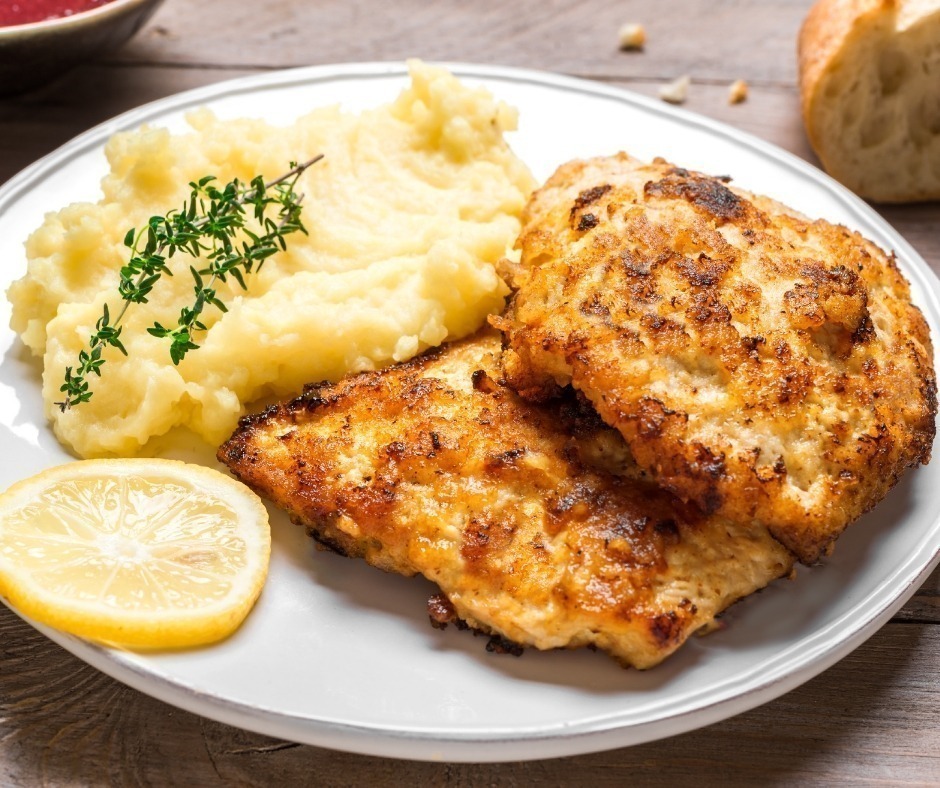 Mashed potatoes with fried chicken cutlets and lemon slices.