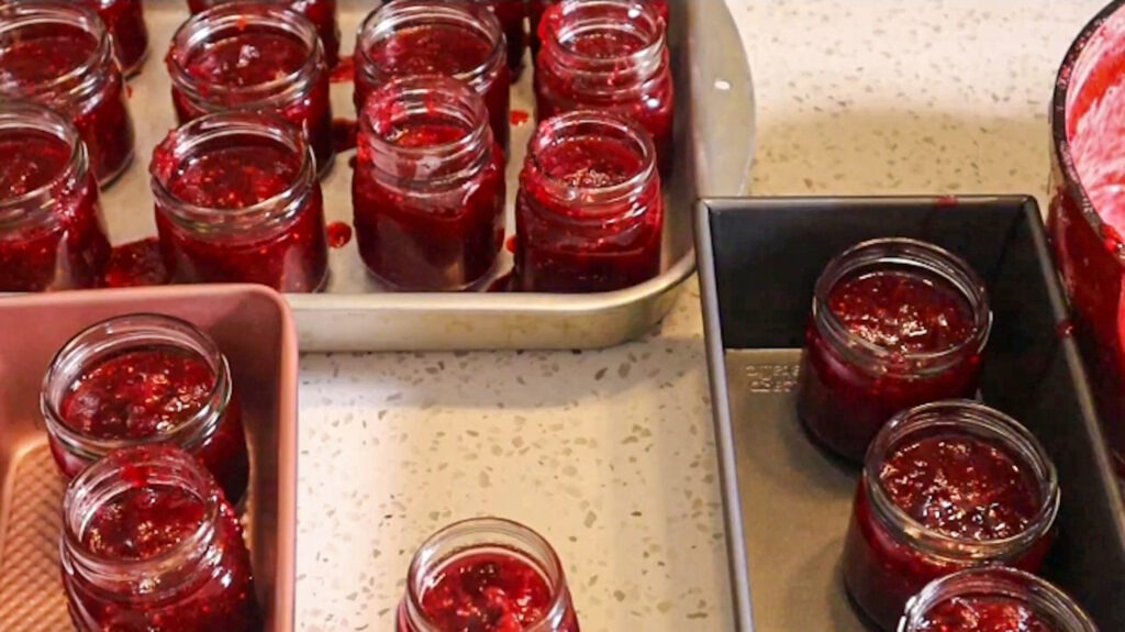Adding the strawberry cranberry jam to sterilized jars.