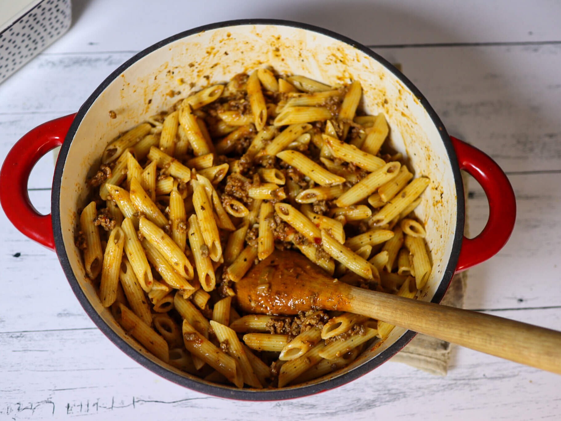 Mixing the penne pasta with meat sauce.