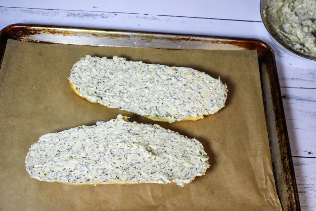 Spreading garlic butter onto the bread.