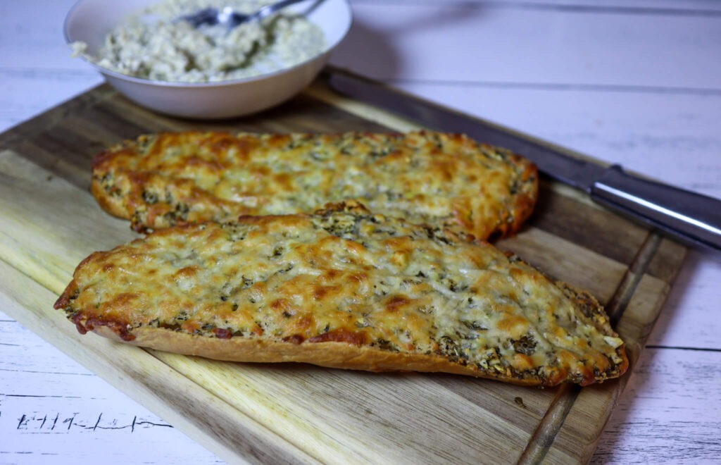 Cheesy garlic bread on a cutting board with garlic butter.
